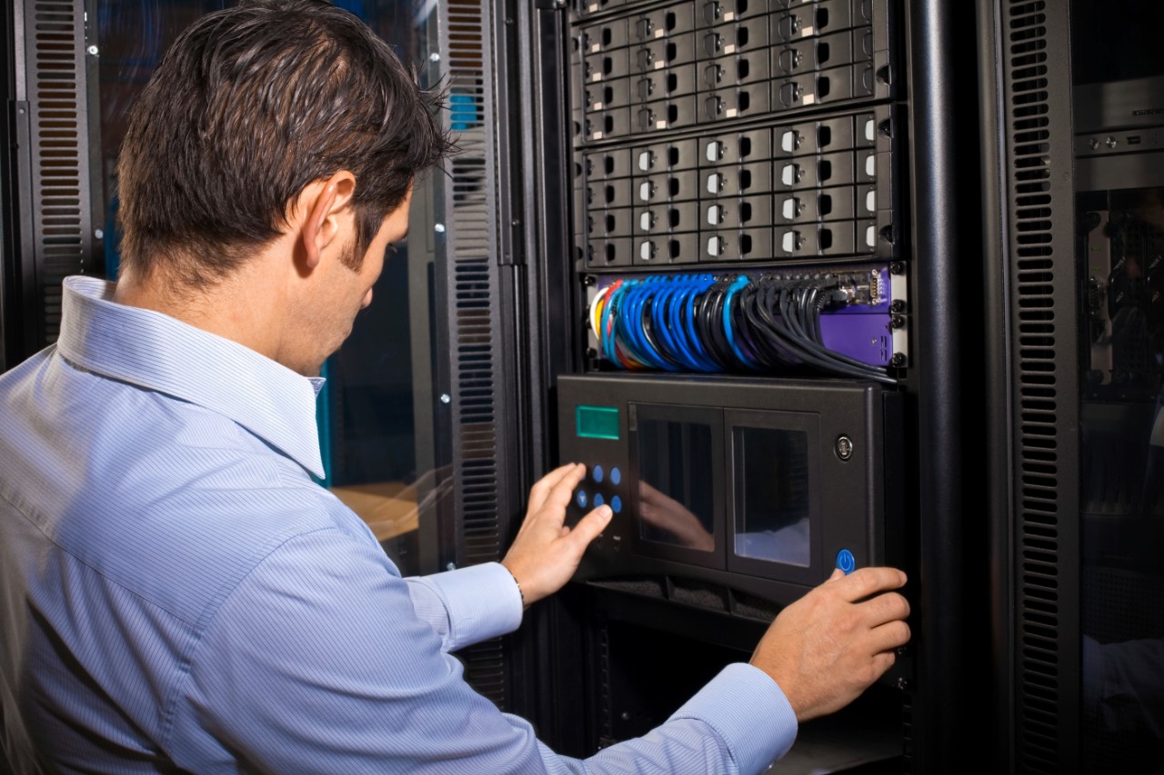 An IT technician programming computer equipment in a server room