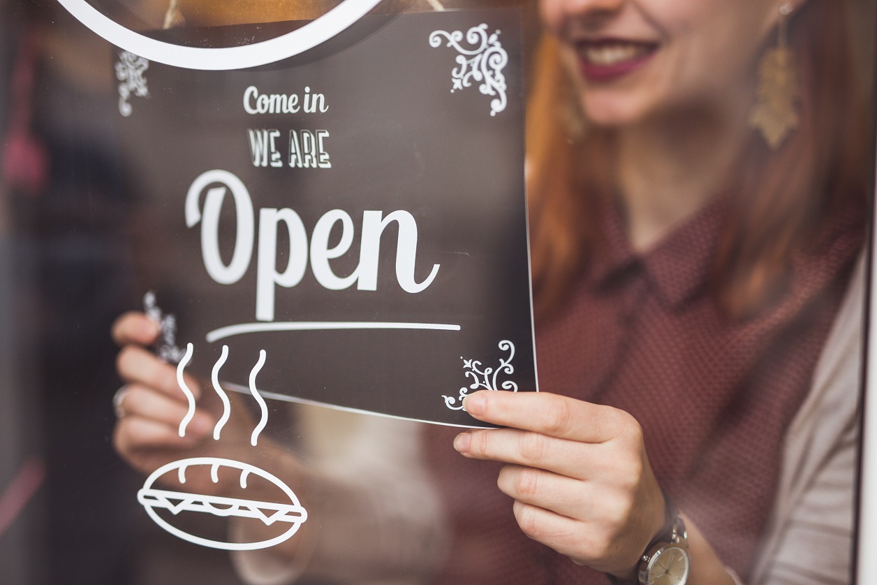 Beautiful Young Woman Setting Open Sign On Store Window